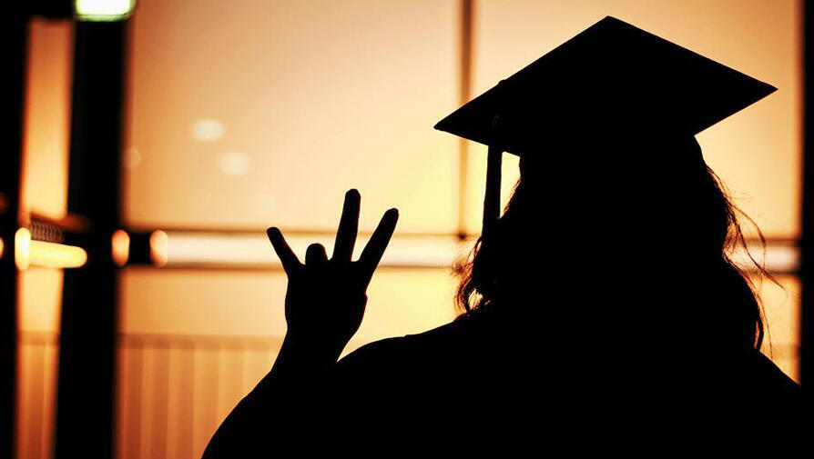Silhouette of student with graduation cap on gold background